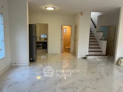 Spacious open-plan living area with marble flooring and staircase