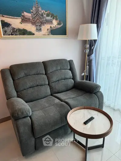 Cozy living room with plush sofa, elegant lamp, and scenic wall art near a large window.