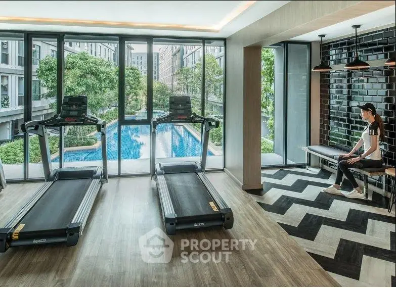 Modern gym with treadmills and pool view in luxury apartment complex