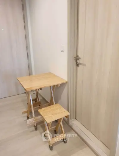 Compact wooden table and stool set in a modern apartment hallway with light wood flooring.