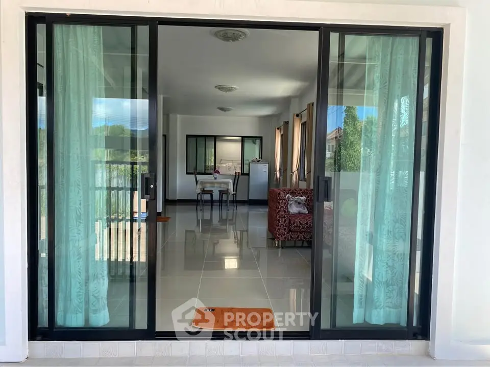 Spacious living room with sliding glass doors and elegant curtains, offering a seamless indoor-outdoor flow.