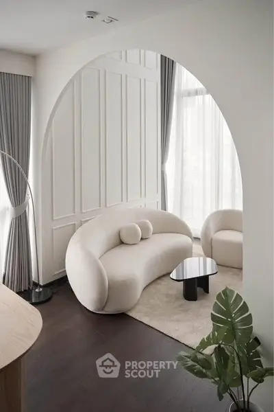 Elegant modern living room with curved sofa, floor-to-ceiling windows, and stylish decor.