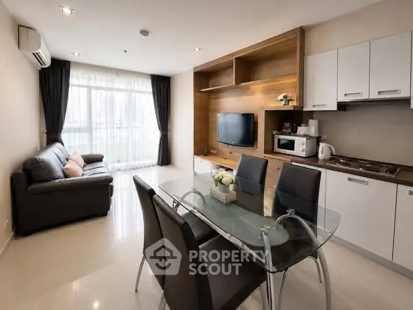 Modern living room with open kitchen, glass dining table, and cozy seating area.