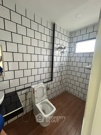 Modern bathroom with stylish white tiles and wooden flooring