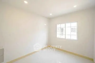 Bright empty room with large window and white walls, perfect for customization.