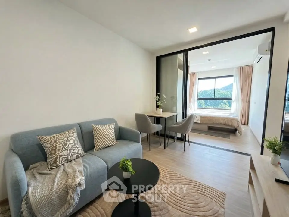 Modern open-plan living room with cozy seating and scenic bedroom view