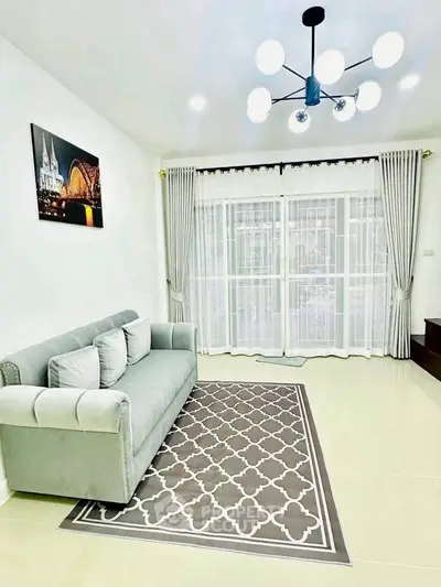 Elegant living room with modern chandelier and plush sofa, featuring large windows and stylish decor.