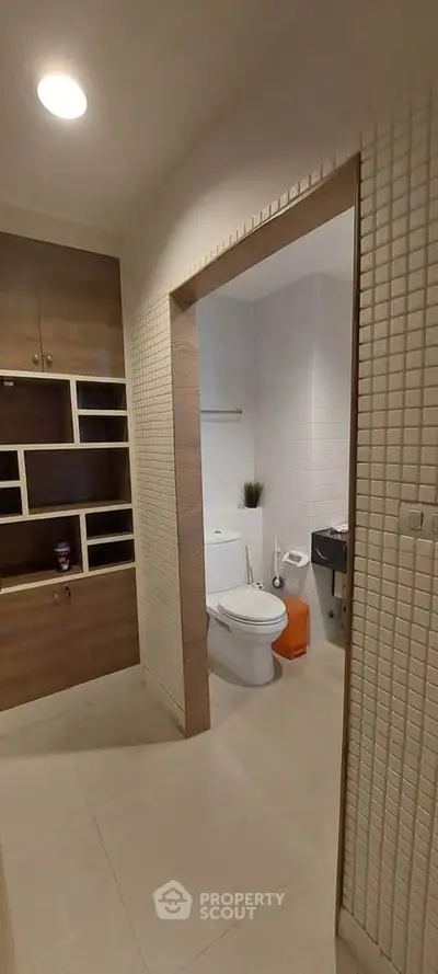 Modern bathroom with wooden shelving and tiled walls in a stylish apartment.