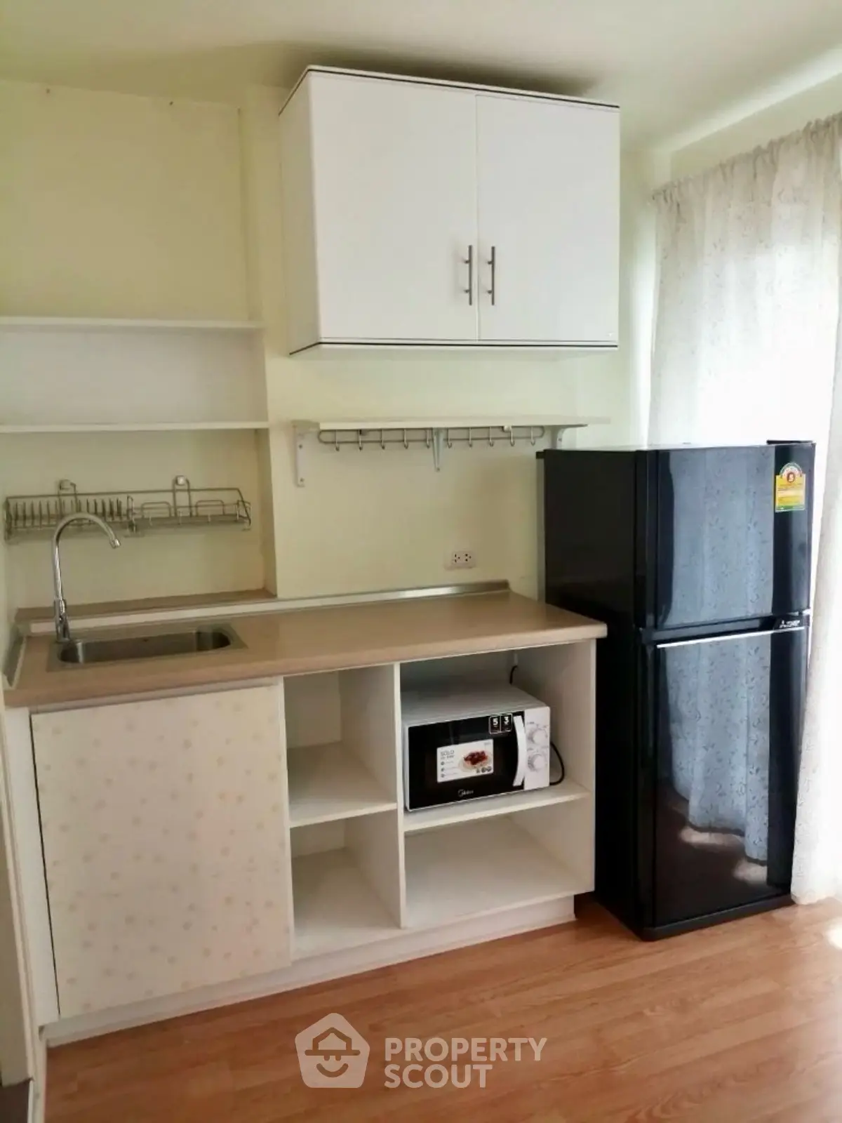 Modern kitchen with sleek black fridge and microwave in compact layout