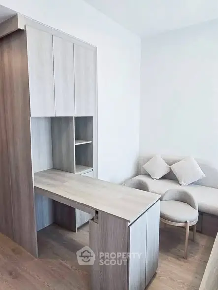 Modern minimalist living room with sleek wooden furniture and cozy seating area.