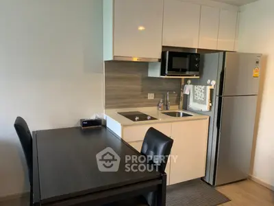 Modern kitchen with sleek cabinetry and dining area, featuring a compact design and stainless steel appliances.