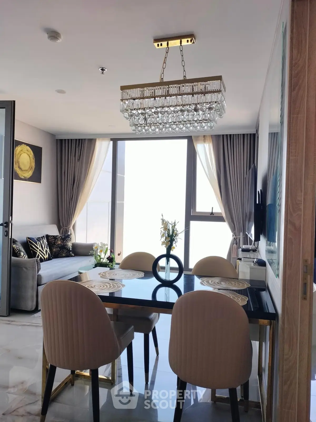 Luxurious dining area with elegant chandelier and modern decor in a high-rise apartment.