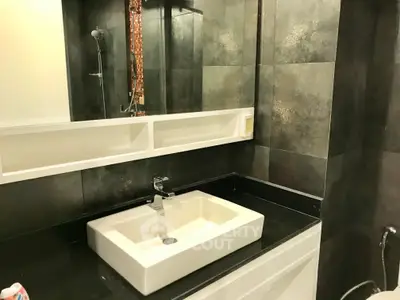 Modern bathroom with sleek sink and stylish dark tiles