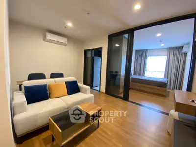 Modern living room with open view to bedroom, featuring stylish furniture and wooden flooring.