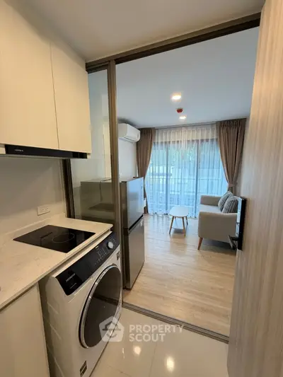 Modern apartment with open kitchen and cozy living room, featuring a washing machine and stylish decor.