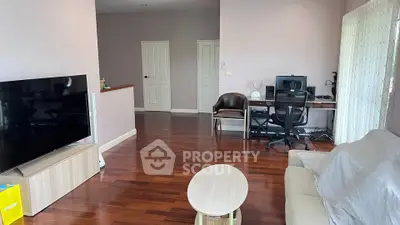 Spacious living room with hardwood floors, modern furniture, and a large TV, perfect for relaxation.