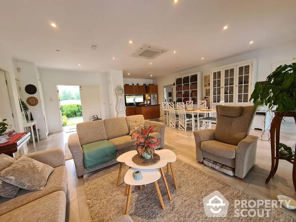 Spacious and bright open-plan living area with plush seating, elegant decor, and seamless transition to a modern kitchen, perfect for entertaining.