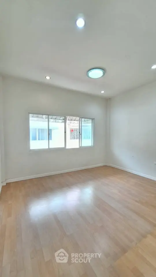 Spacious empty room with wooden flooring and large windows, ideal for customization.