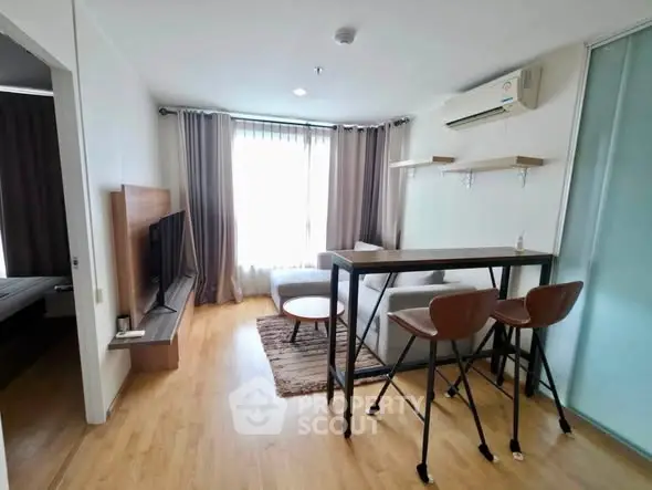 Modern living room with stylish furniture and natural light, featuring a cozy seating area and sleek wooden flooring.