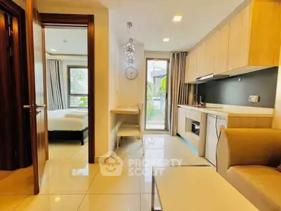 Modern open-layout apartment with sleek kitchen and cozy living area, featuring natural light and stylish decor.