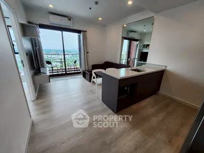 Modern living room with open kitchen and balcony view in high-rise apartment.