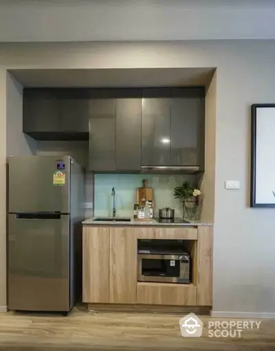 Modern compact kitchen with sleek cabinets and stainless steel fridge