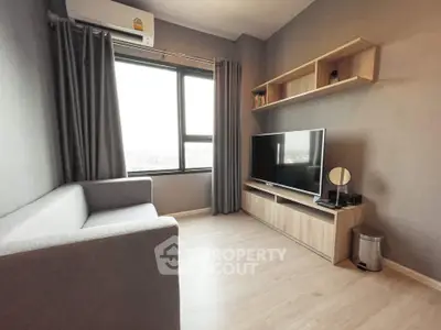 Modern living room with sleek furniture and large window offering natural light.