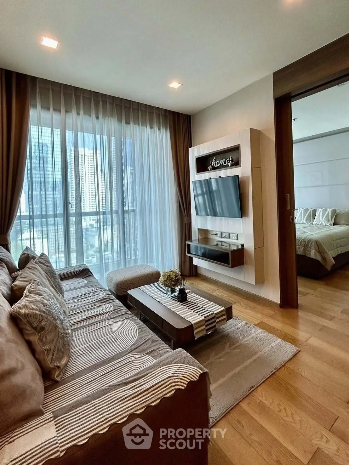 Modern living room with city view, cozy sofa, and stylish decor in a high-rise apartment.