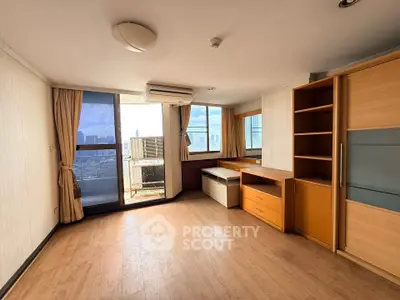Spacious living room with wooden flooring and city view balcony in modern apartment.