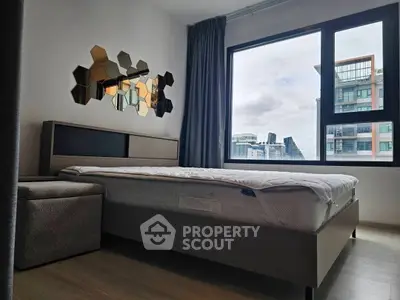 Modern bedroom with stylish decor and large window offering city views