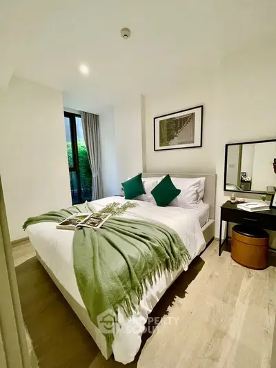 Cozy bedroom with modern decor, featuring a comfortable bed, stylish green accents, and a serene view.