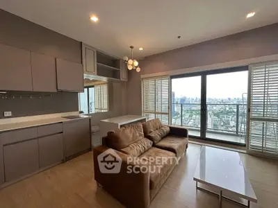 Modern living room with city view, featuring a cozy brown sofa and sleek kitchen area.