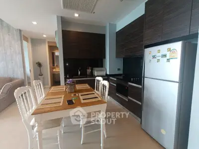 Modern kitchen with sleek cabinets, dining table, and stainless steel appliances in a stylish apartment.