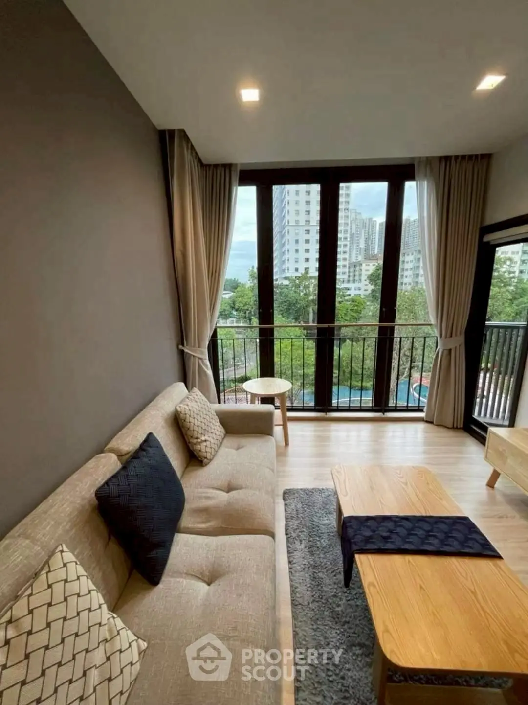 Modern living room with large windows and city view, featuring stylish furniture and cozy decor.