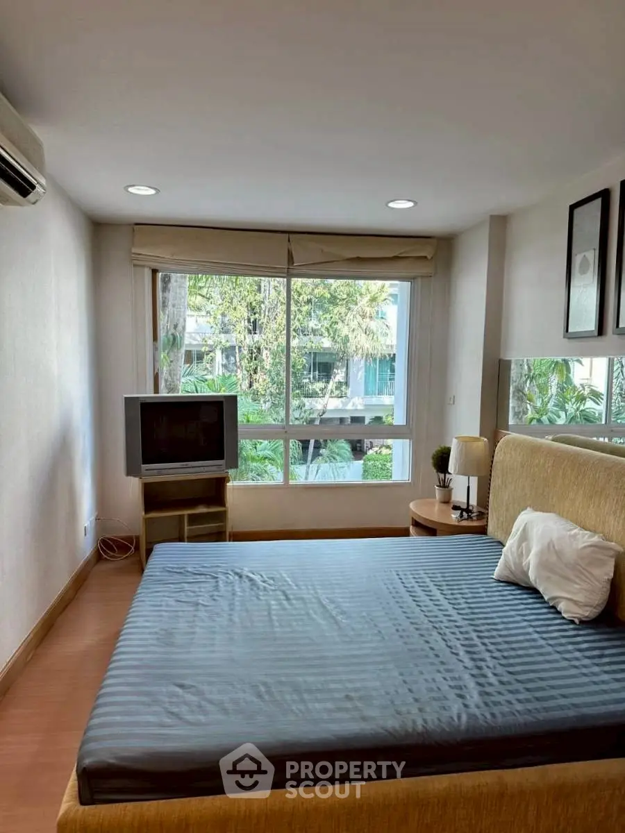 Cozy bedroom with large window and garden view, featuring a comfortable bed and modern decor.