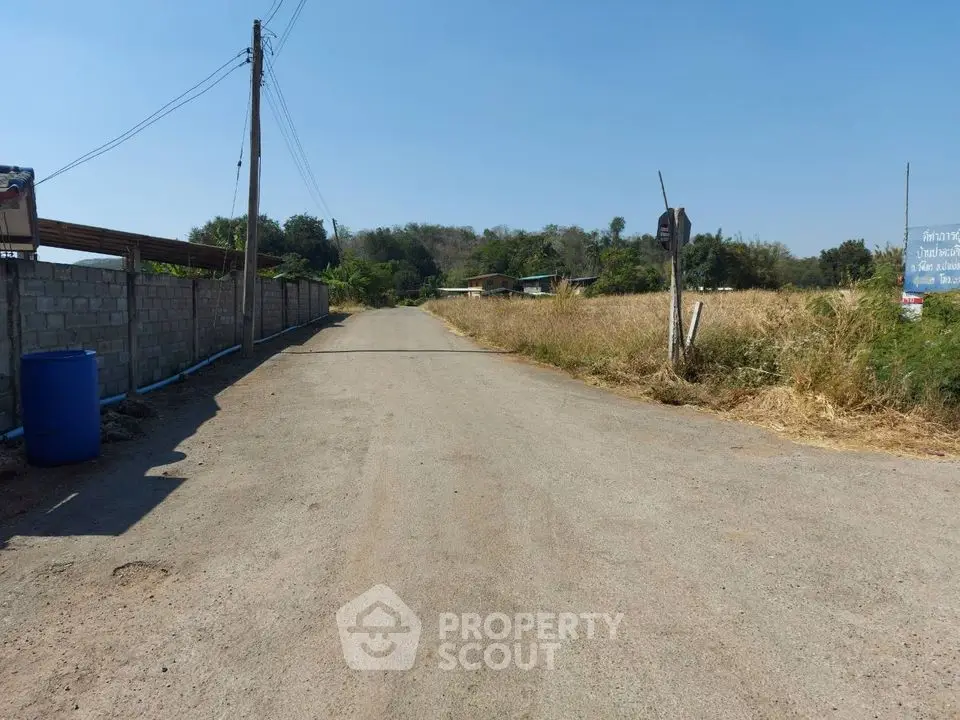Scenic rural road with open fields and distant hills, ideal for countryside living.