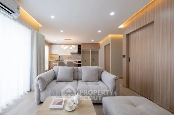 Modern living room with cozy sofa, elegant lighting, and open kitchen layout.