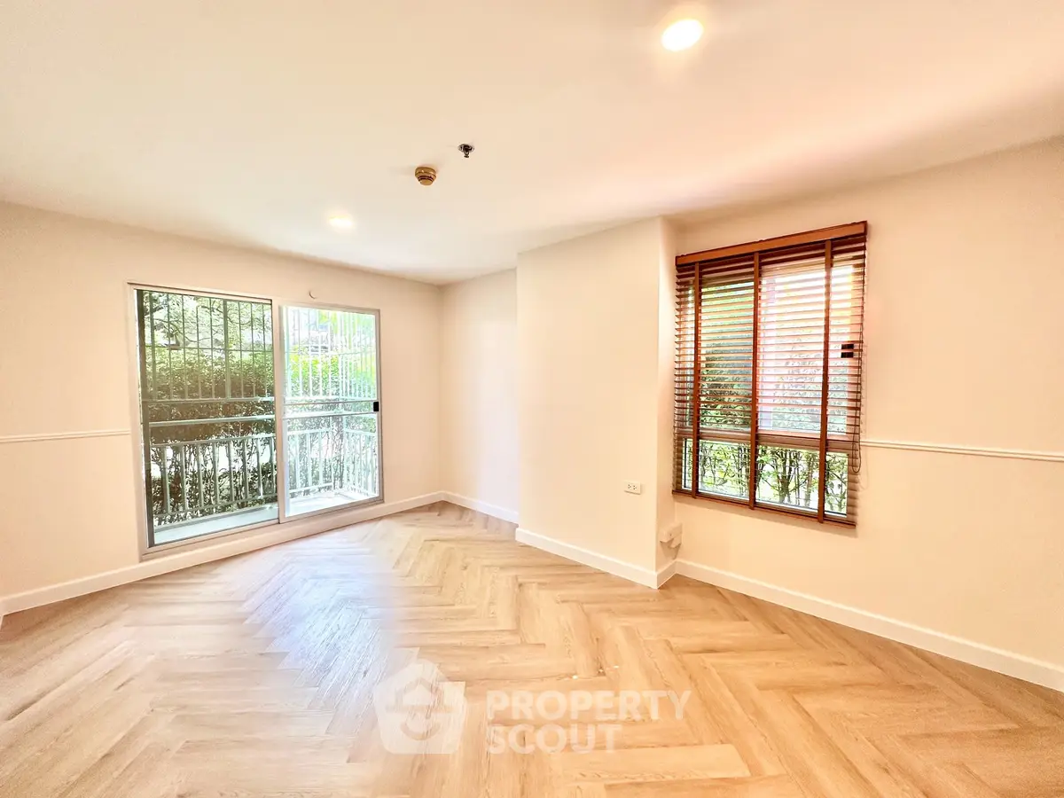Bright and spacious living room with large windows and elegant wooden flooring.