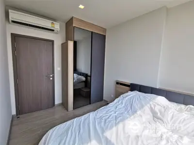 Spacious bedroom with modern mirrored wardrobe and wooden flooring, offering a serene and comfortable living space.