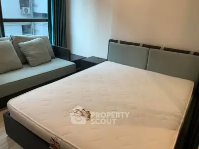 Modern bedroom with stylish bed and cozy sofa in a well-lit apartment.