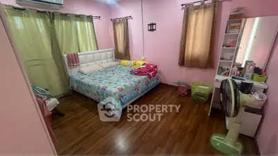 Cozy bedroom with pink walls, wooden flooring, and ample natural light from large windows.
