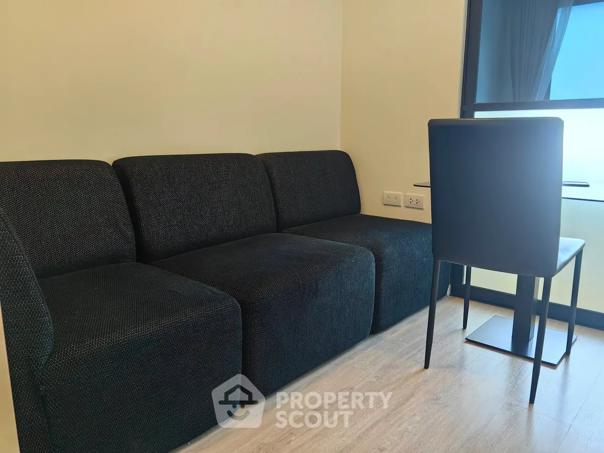 Modern living room with sleek black sofa and dining chair by window