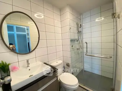 Modern bathroom with glass shower and sleek vanity in contemporary apartment.