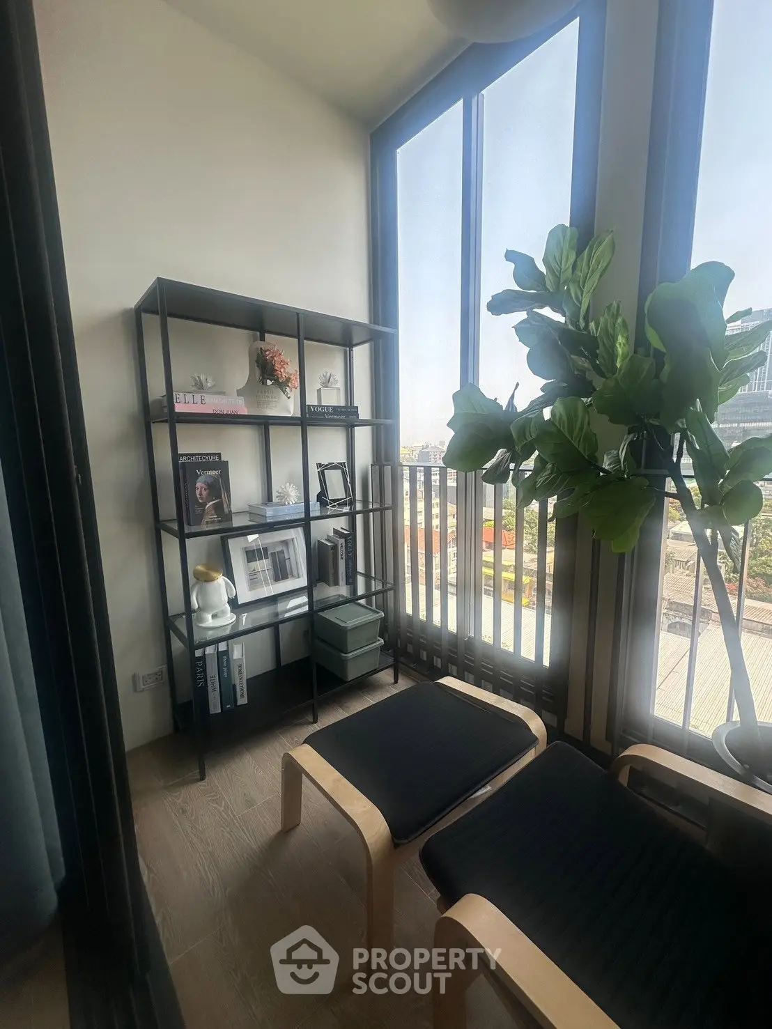 Chic balcony with modern seating and bookshelf, offering a serene view for relaxation.