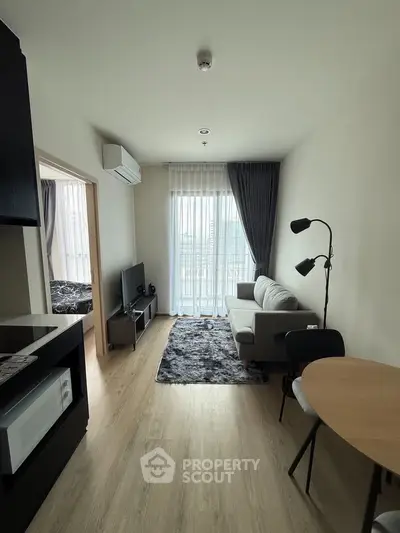 Modern living room with cozy sofa, stylish decor, and natural light from large window.