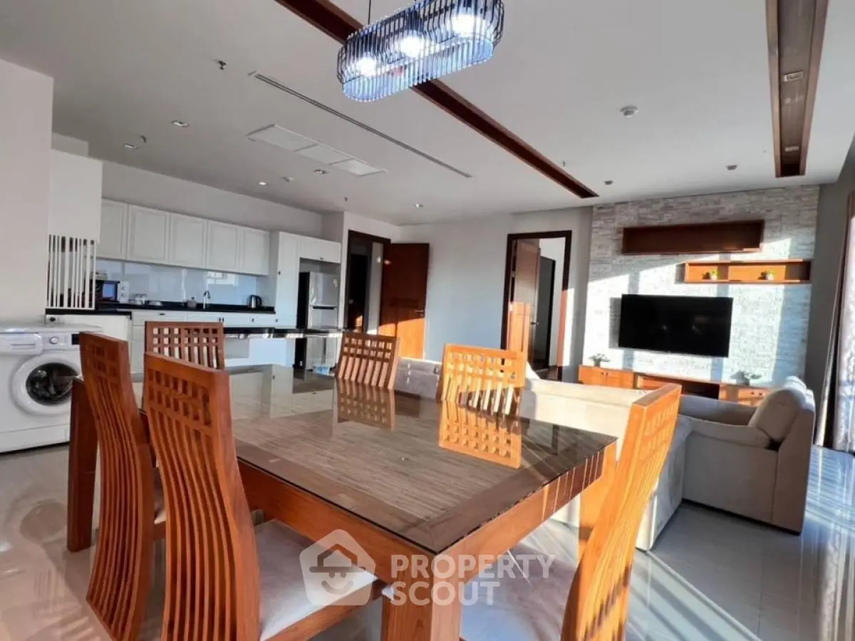 Spacious modern living room with open kitchen and elegant dining area, featuring natural light and stylish decor.