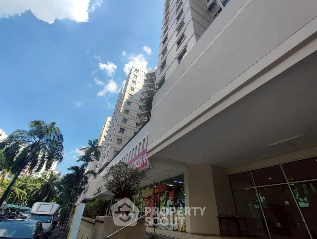 Modern high-rise building exterior with lush greenery and clear blue sky