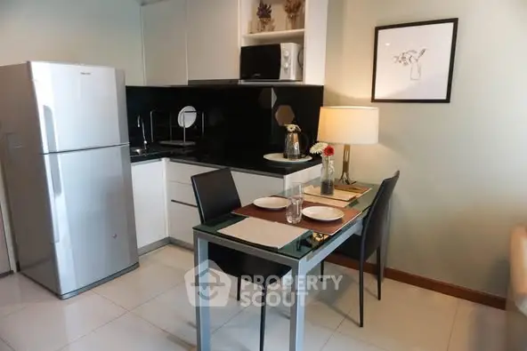 Modern kitchen with sleek appliances and cozy dining area in a stylish apartment.