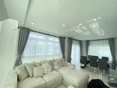 Spacious modern living room with large windows and elegant dining area