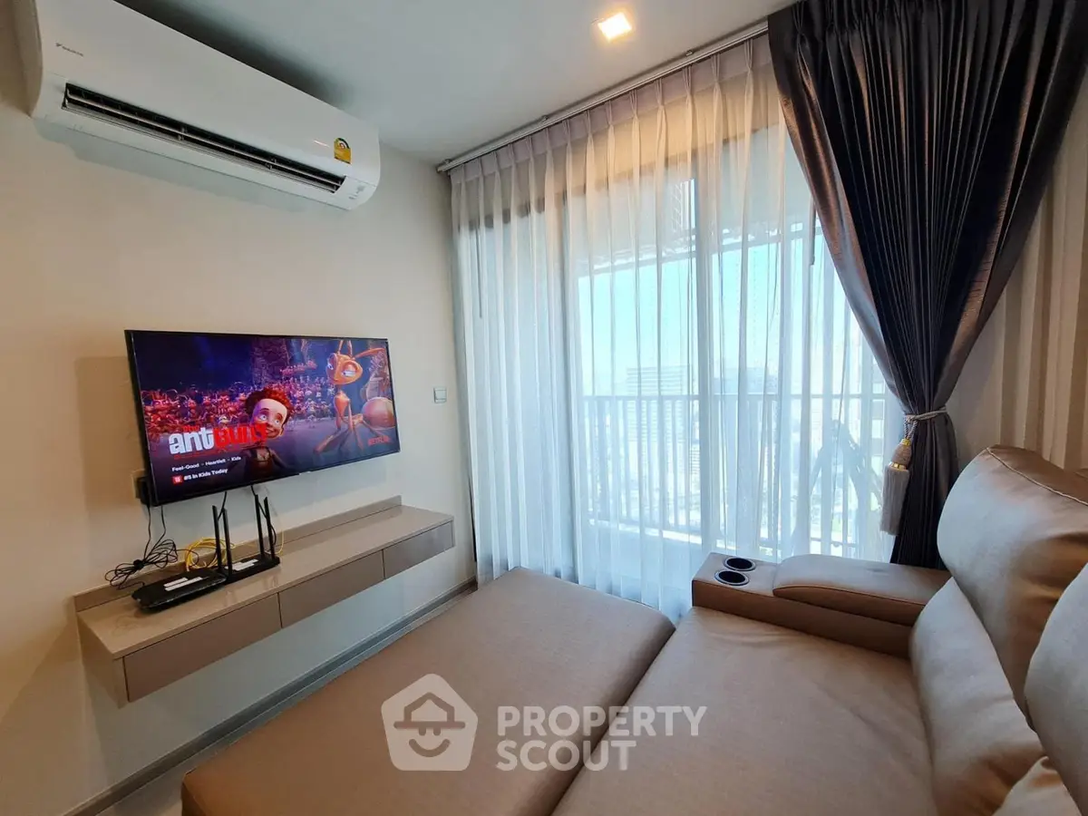 Modern living room with sleek sofa, wall-mounted TV, and large window with city view.